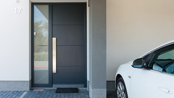 Entranceway to a home displaying a large black door with a stainless steel handle.