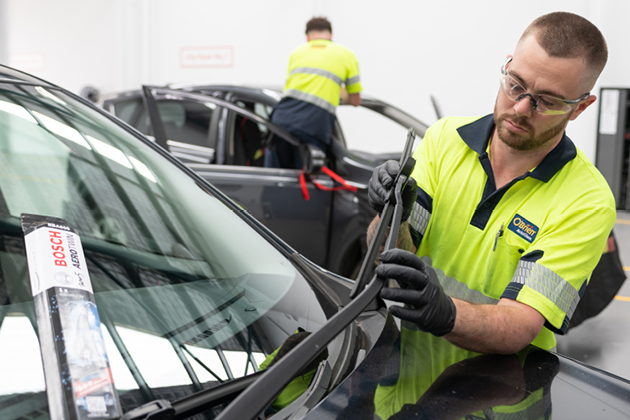 O'Brien® staff member replacing windscreen wipers on a black vehicle.