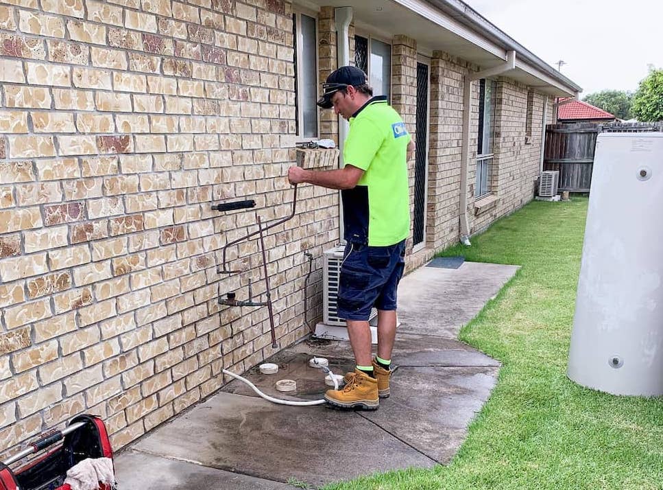 Plumber working on a hot water system at a home on the Sunshine Coast