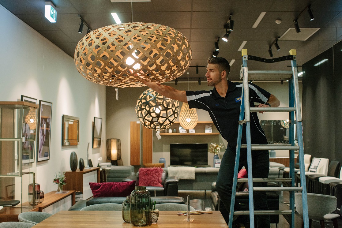 An electrician installing commercial lighting in a retail space in Camberwell