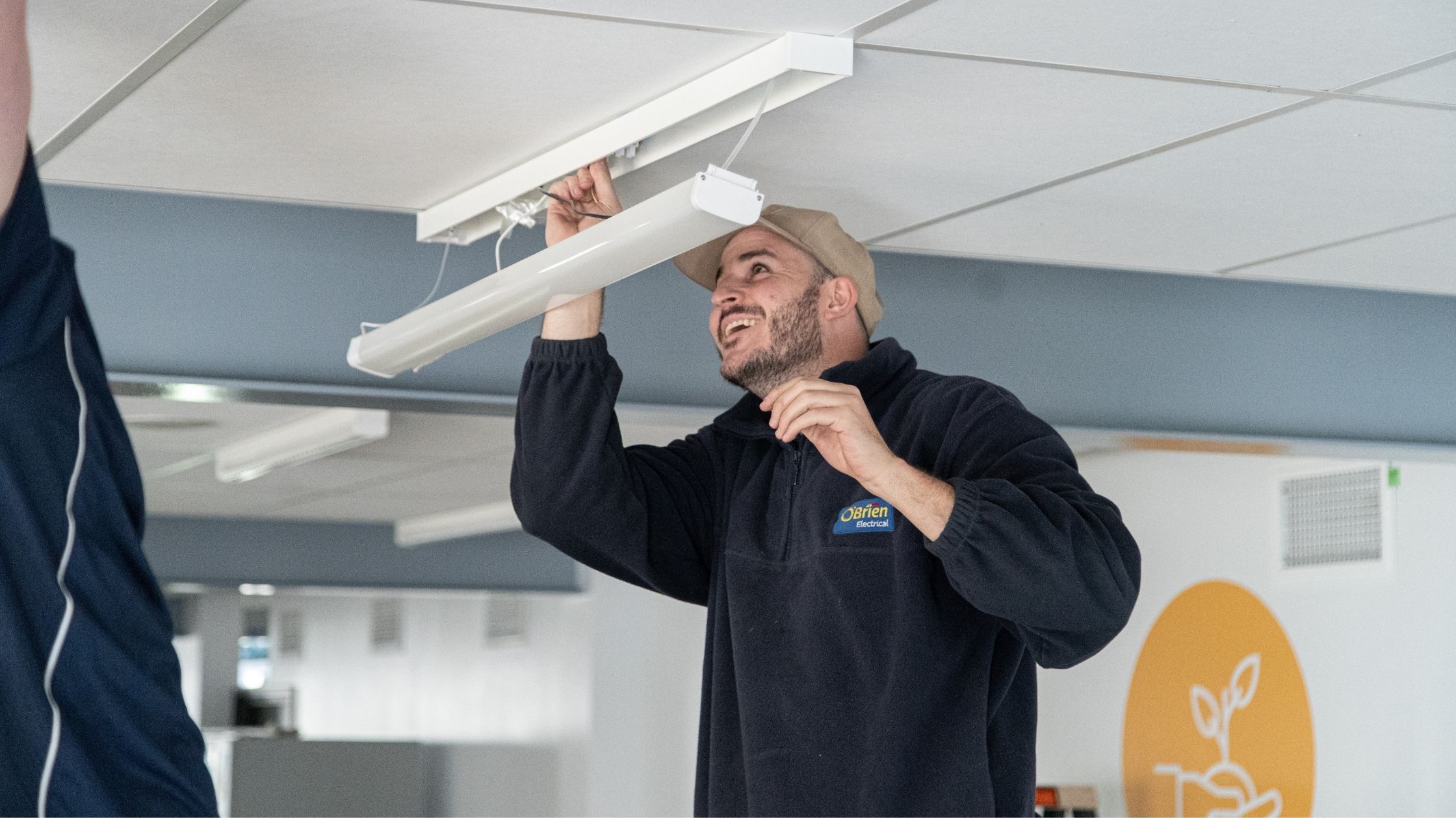 An electrician fixing a commercial light as part of electrical maintenance services in Rowville