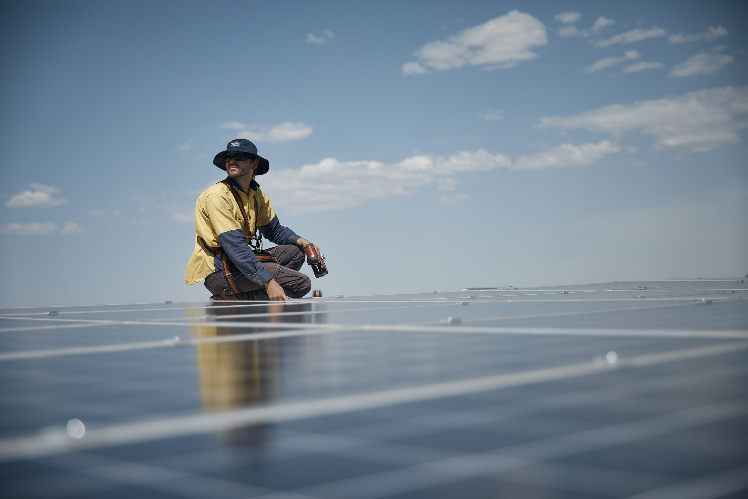 An electrician on a roof installing industrial solar panels
