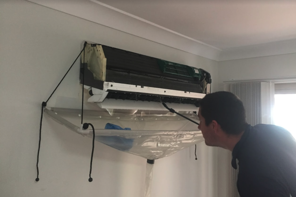 An electrician cleaning an air conditioner in a home on the Sunshine Coast