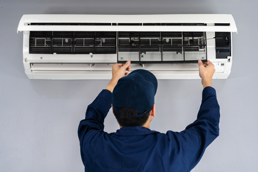 An electrician completing an air conditioner service in a home