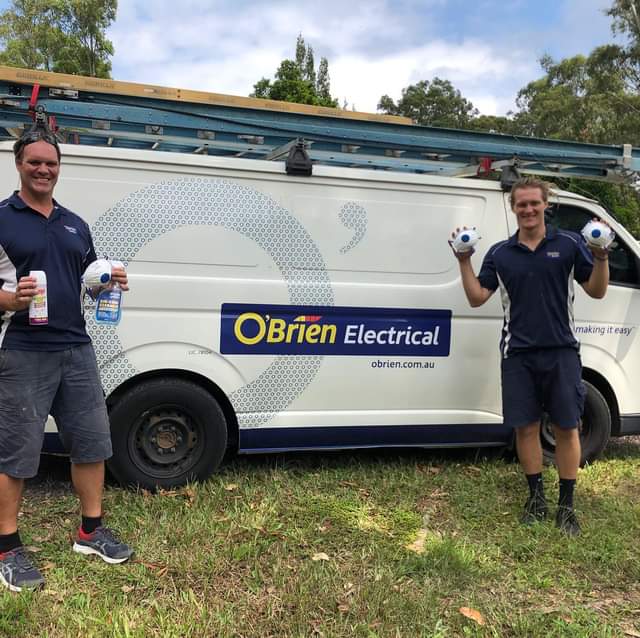 Electricians holding security cameras in front of their van in Noosa