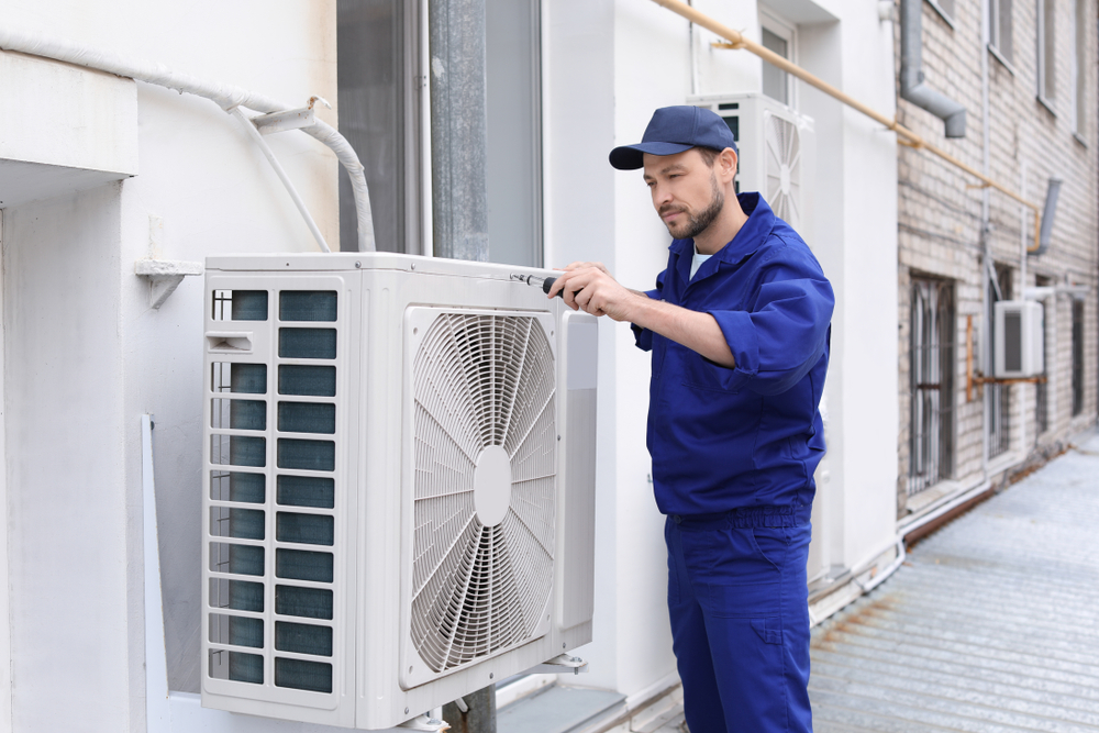 male-technician-repairing-air-conditioner-outdoors