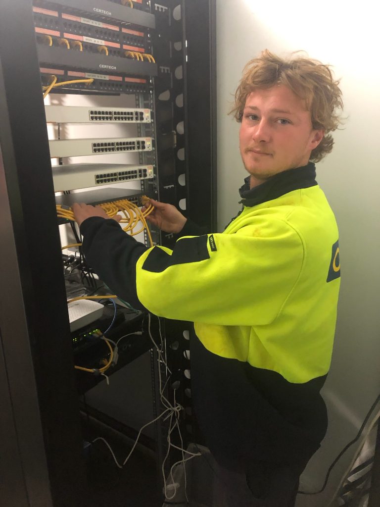 An apprentice building a control panel for data cabling in the Yamba workshop