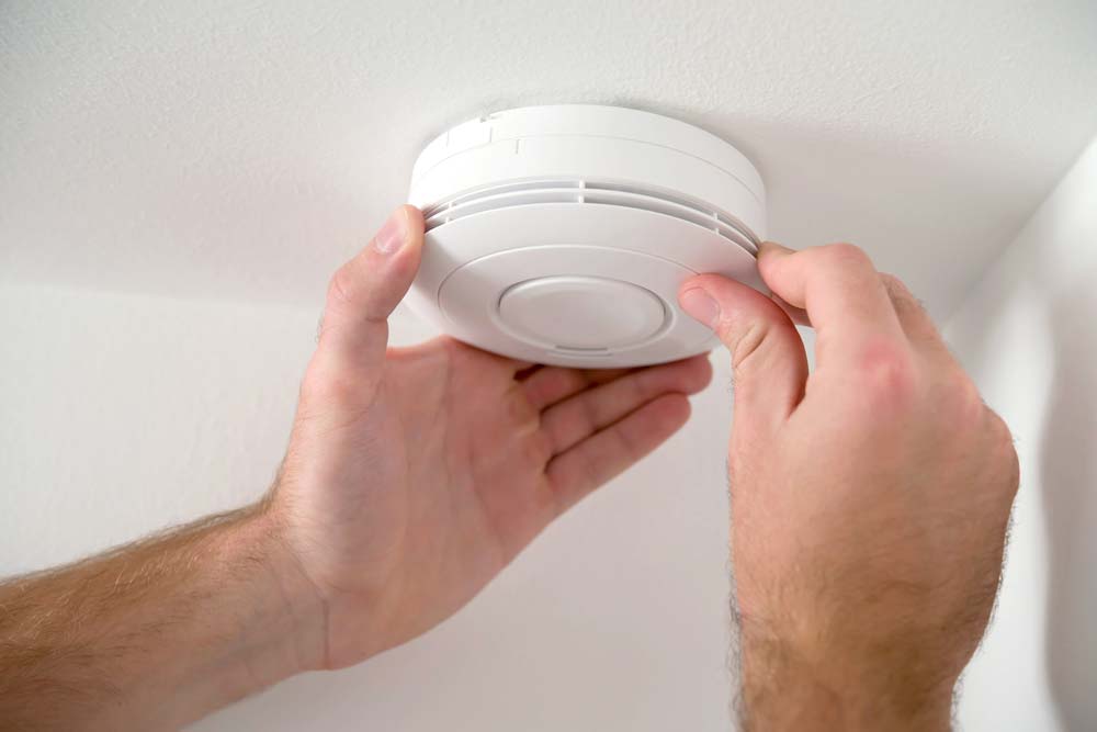 Electrician Installing A Smoke Detector On The Ceiling