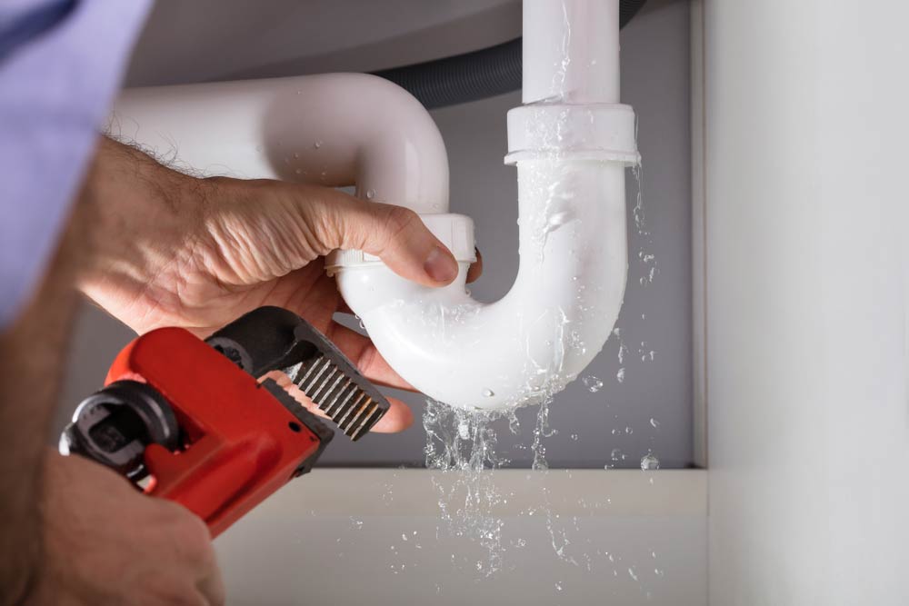 Male Plumber Fixing White Sink Pipe
