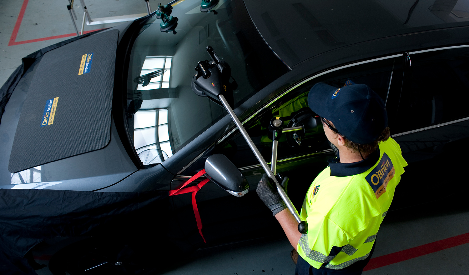 O'Brien® staff member replacing a car windscreen on a black vehicle.