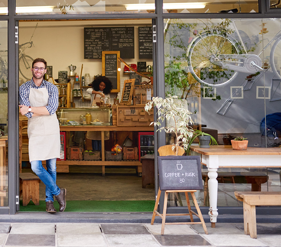 Man standing outside a coffee shop with arms folded.