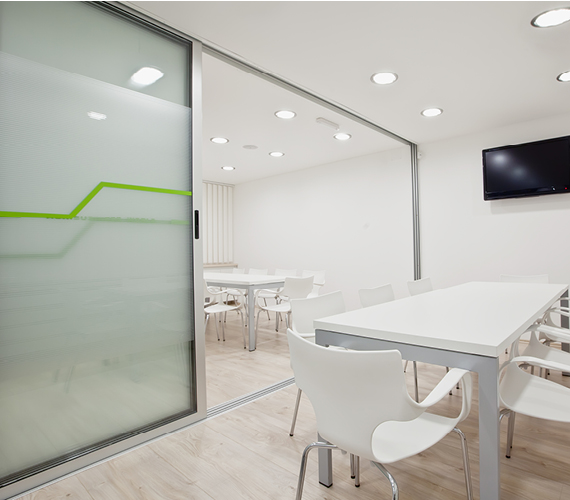 Office boardroom with white desks and chairs.