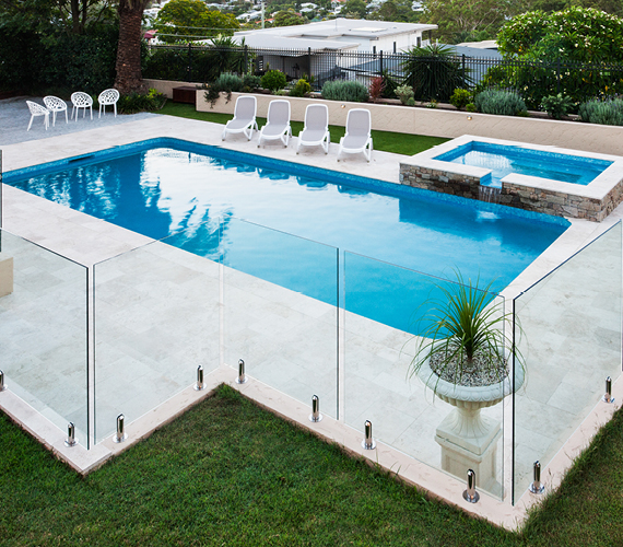 Glass pool fence surrounding a tiled pool area.