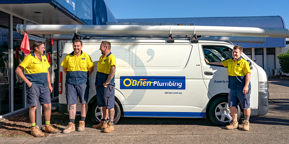 Four O'Brien® staff members standing outside an O'Brien® plumbing van.