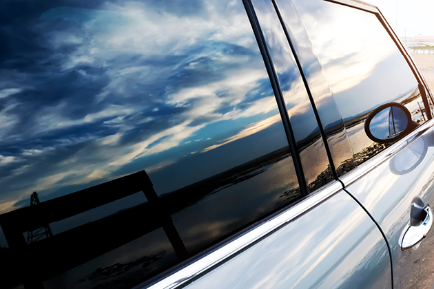 Styled shot of a car body with clouds reflected in the glass.