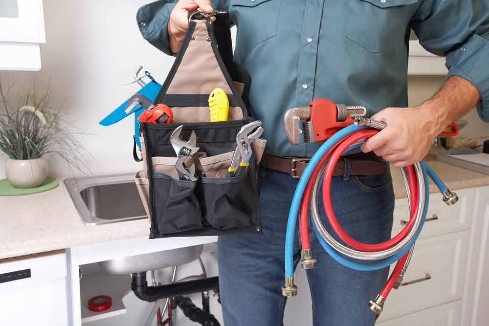 Plumber With Plumbing Tools In The Kitchen
